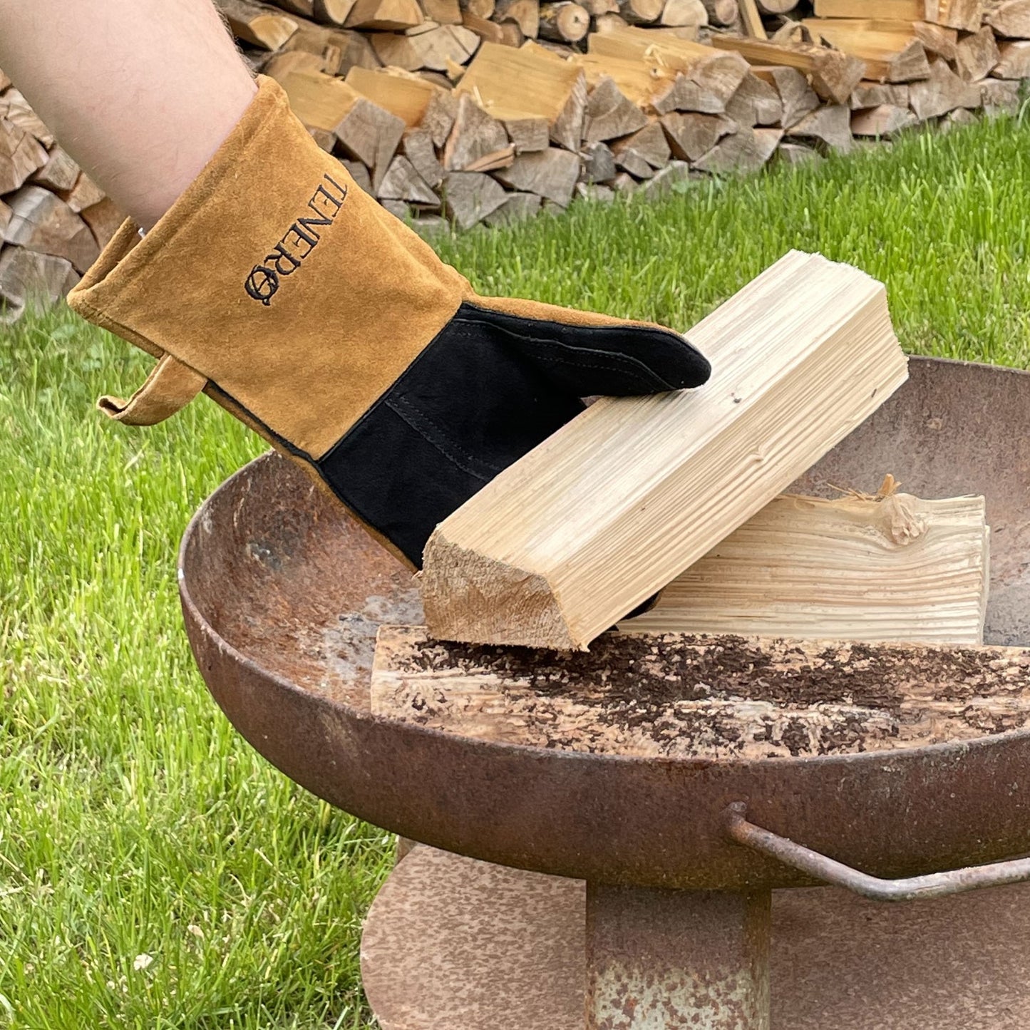 Grillhandschuhe mit Holzscheit am Lagerfeuer
